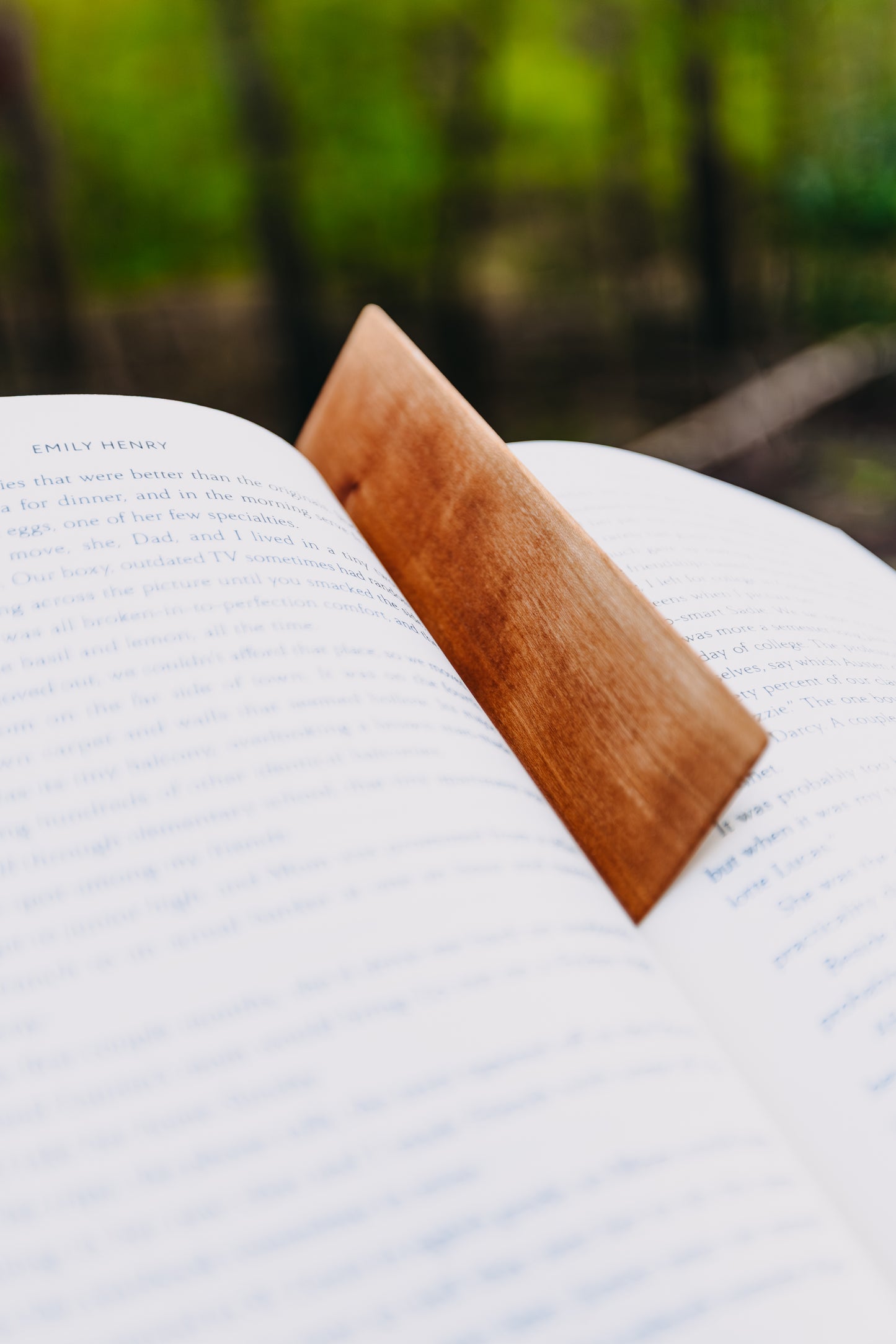 Open book with a wooden cherry edge grain bookmark against a blurred natural background