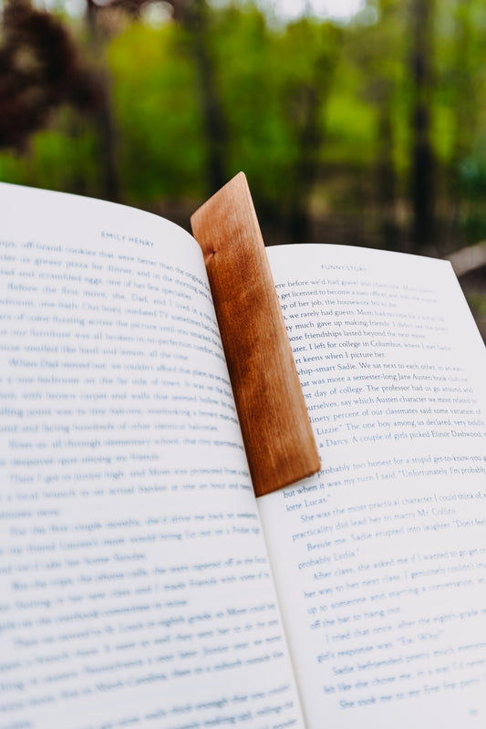 Open book with a wooden cherry edge grain bookmark on a blurred natural background