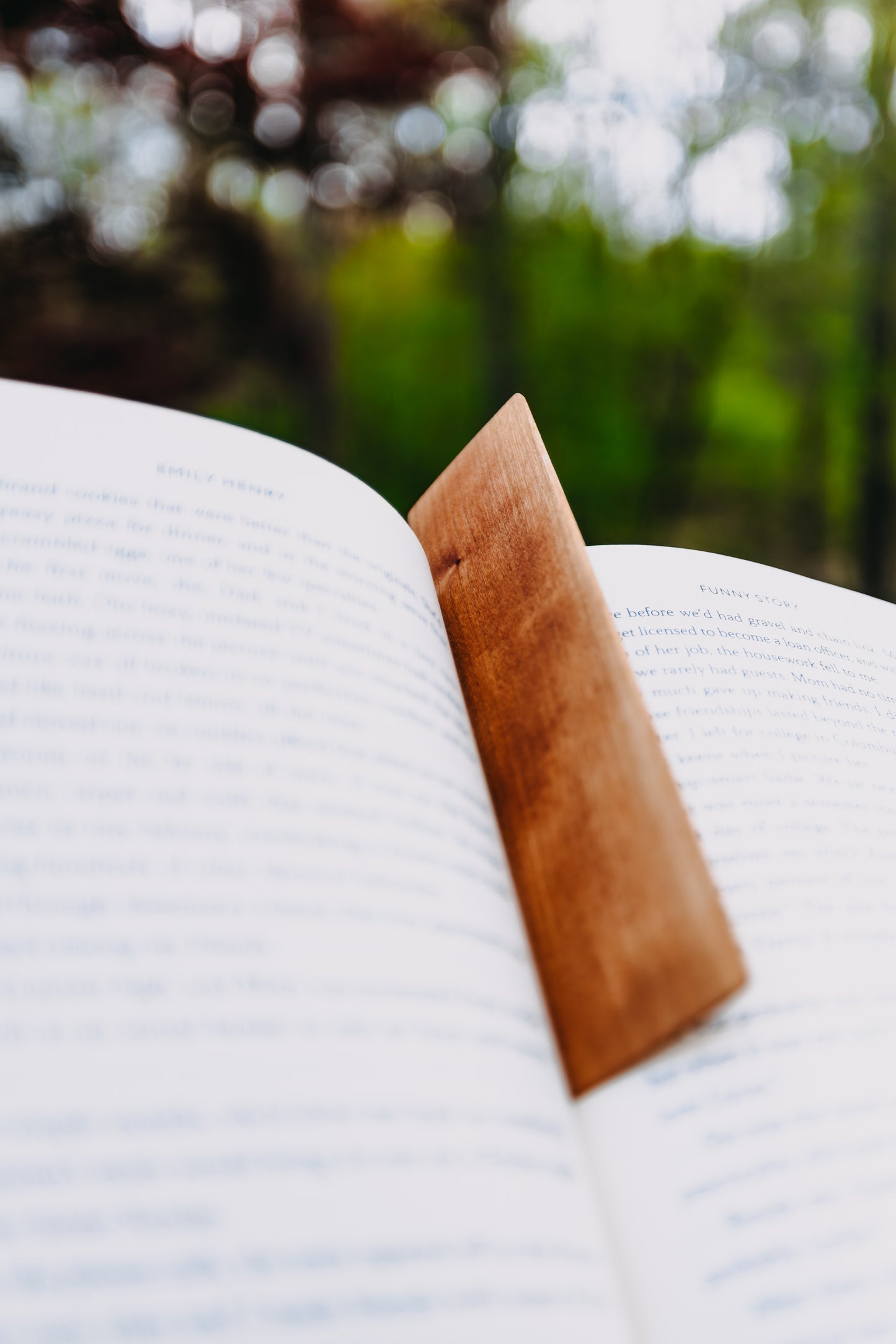Open book with a wooden cherry edge grain bookmark on a blurred natural background