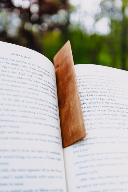 Open book with a wooden cherry edge grain bookmark on a blurred natural background