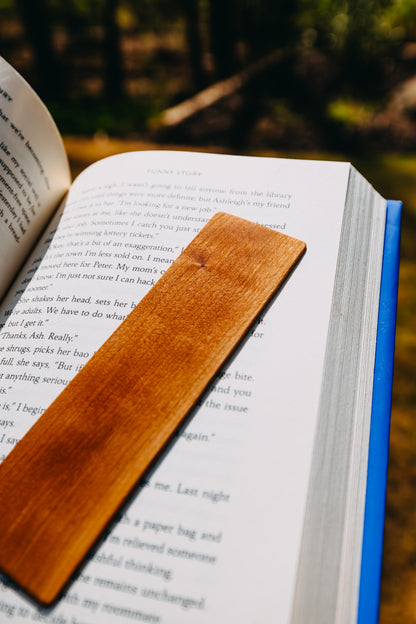 Open book with a wooden cherry edge grain bookmark on a natural background