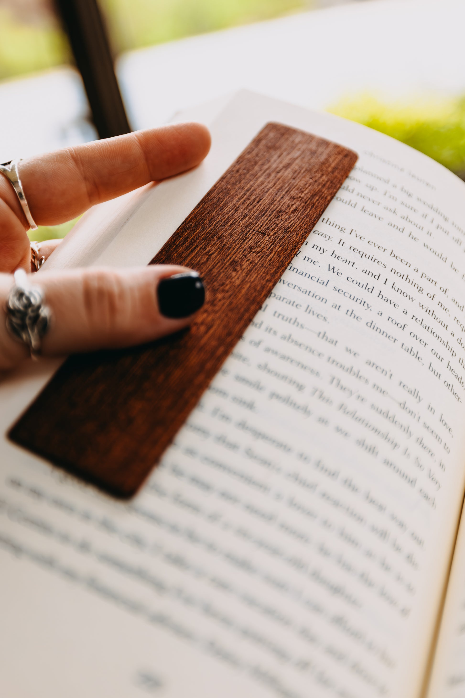 Hand with a wooden sapele edge grain bookmark on an open book