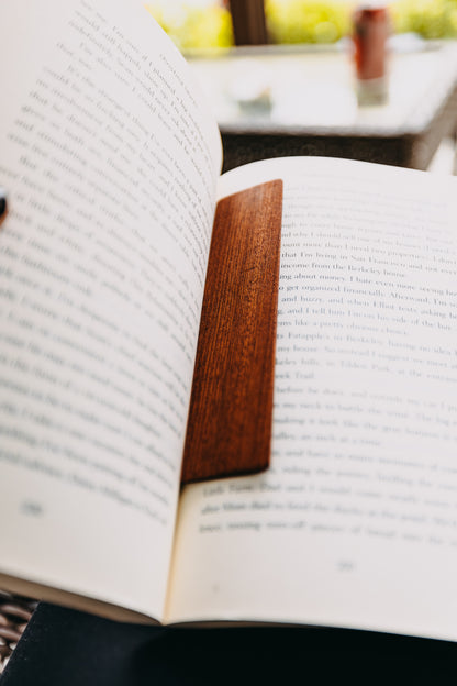 Open book with a wooden sapele edge grain bookmark on a blurred background