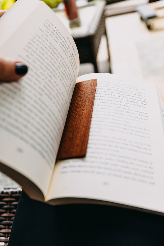 Open book with a wooden sapele edge grain bookmark on a blurred background