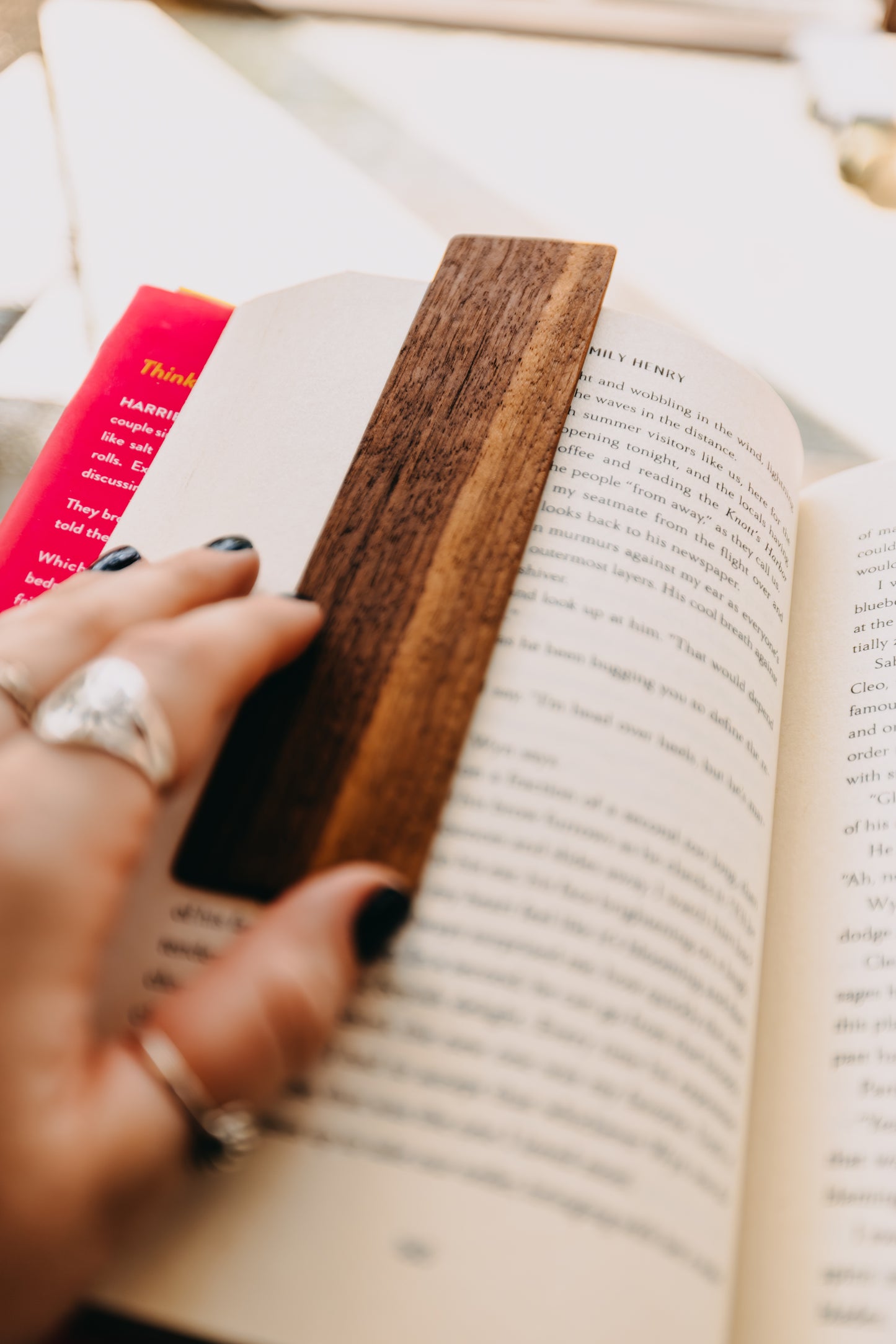Hand holding a wooden black walnut edge grain bookmark in an open book