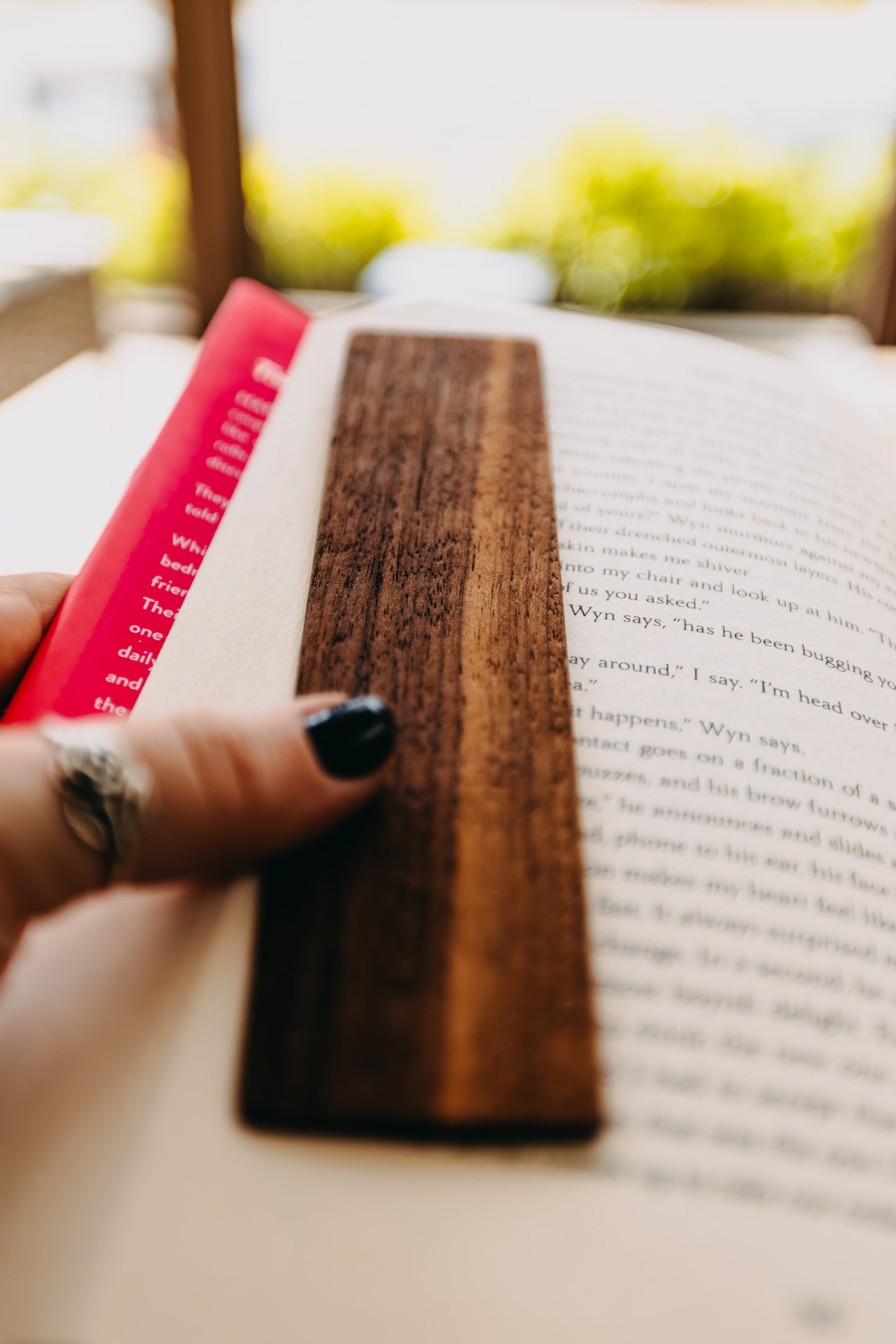 Wooden black walnut edge grain  bookmark on an open book with a blurred background