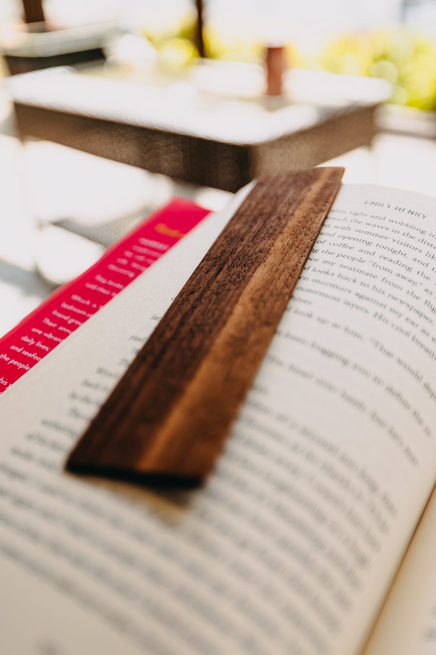 Wooden black walnut edge grain bookmark on an open book with blurred background